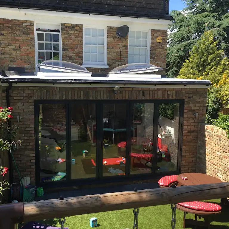 A back garden with a table and chairs.