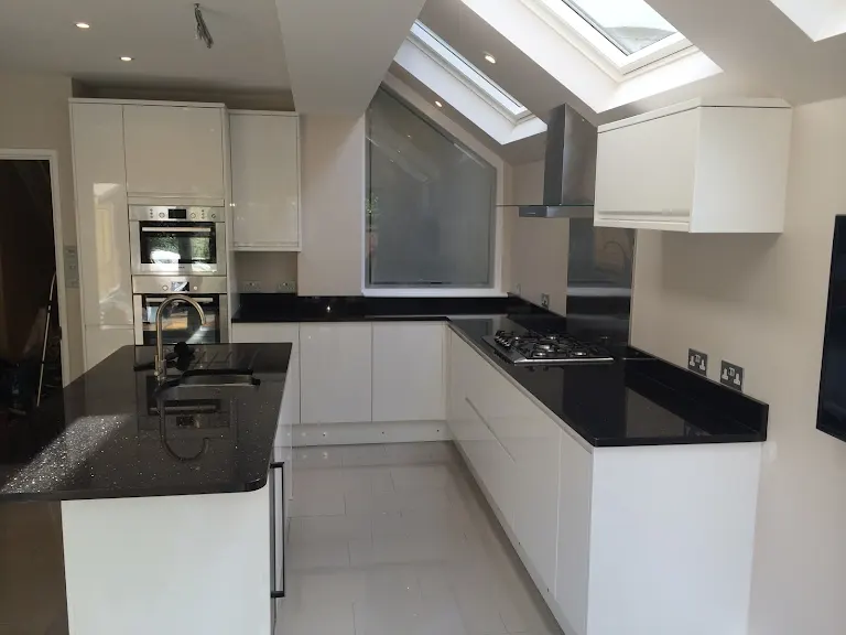 A kitchen with a black counter top and white cabinets.